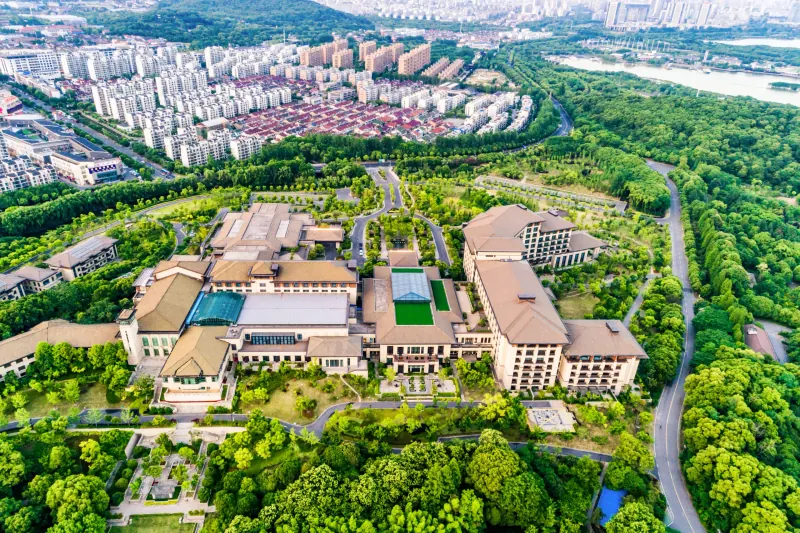Aerial view of a large property with several buildings surrounded by trees and green lawns