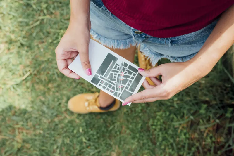 Woman standing on grass holding a printed street map card